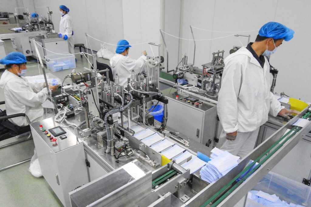 Cleanroom operators operating earloop welding machines on a surgical face mask assembly line