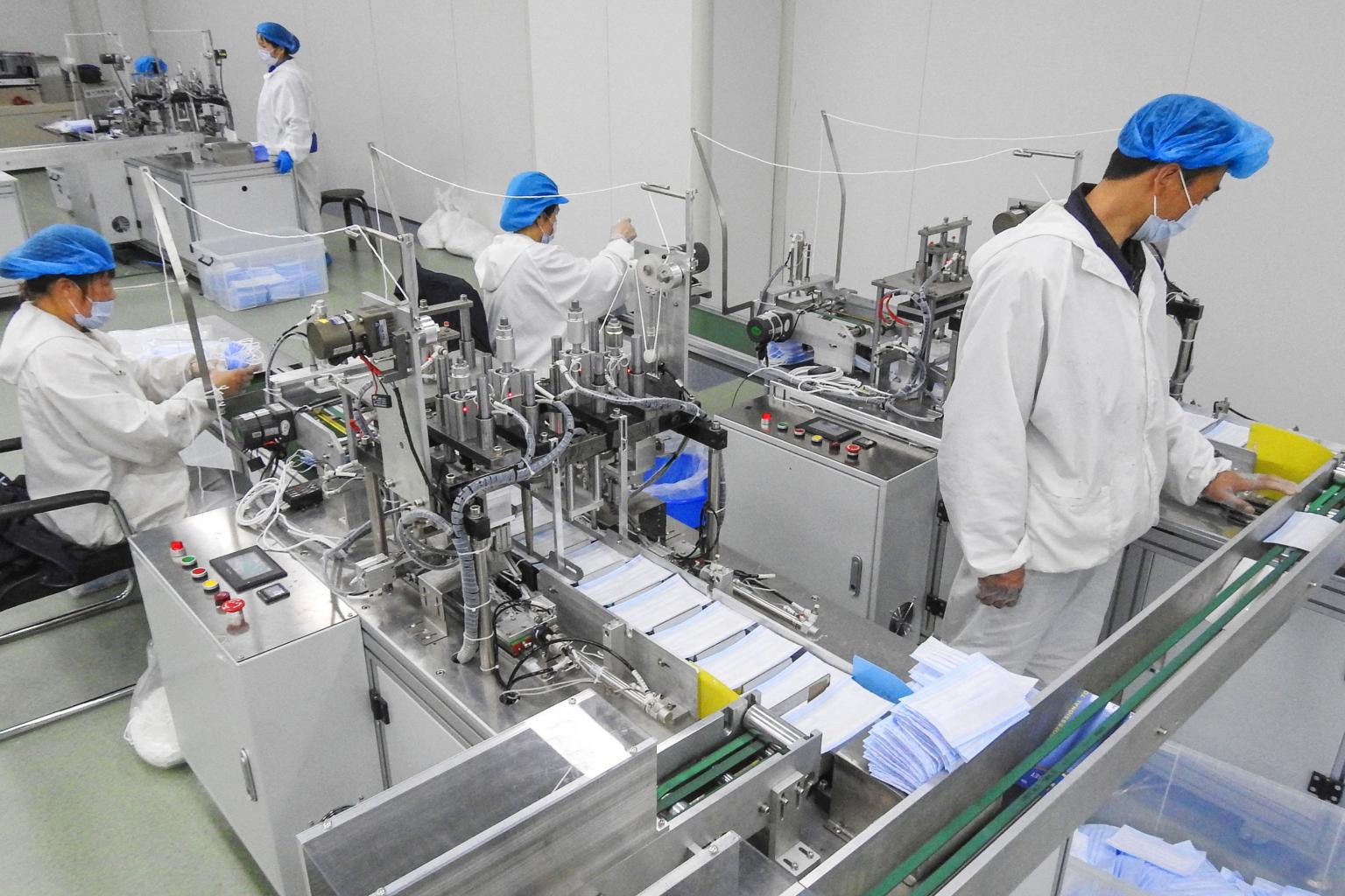 Cleanroom operators operating earloop welding machines on a surgical face mask assembly line